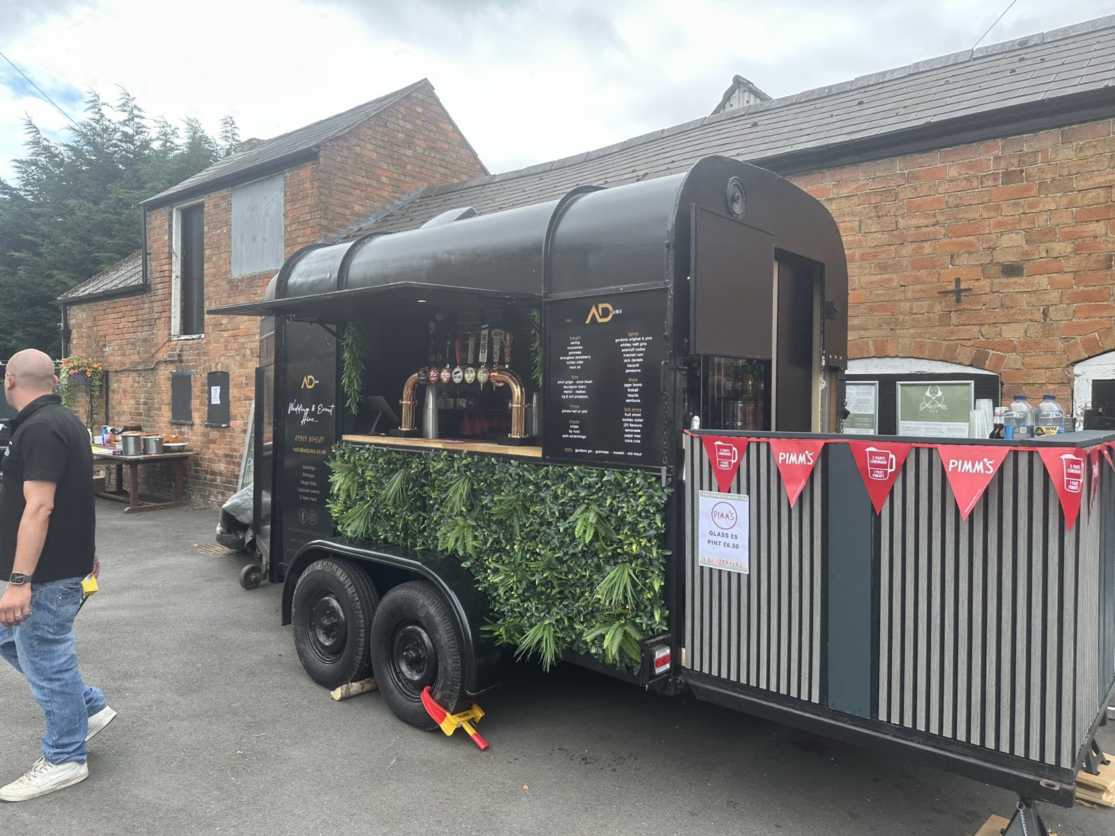The ADpubs mobile horsebox bar, open and serving draught beer, wine and cocktails at an outdoor event.